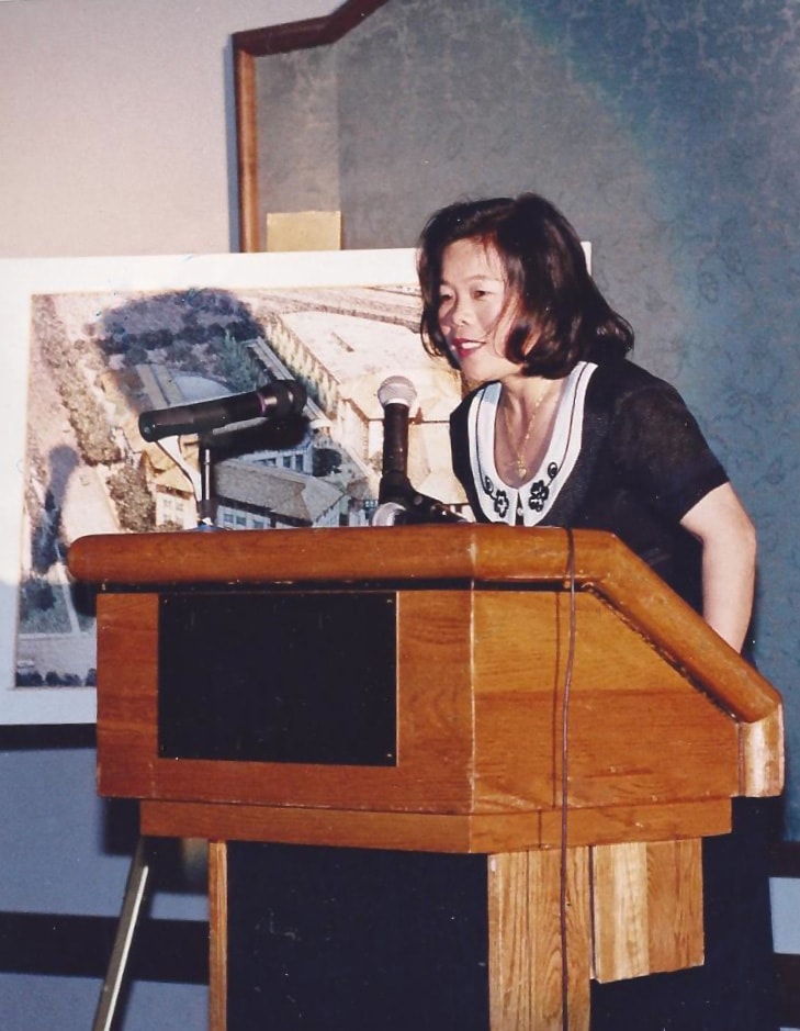 Hoang Taing speaking at a podium during a live event