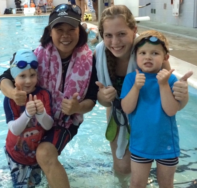 Hoang Taing giving two thumbs up at the pool with children